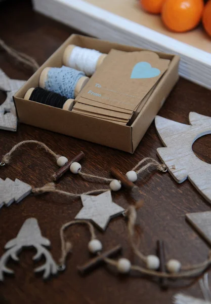 Decoraciones navideñas de madera hechas a mano. Cabeza de ciervo, árboles de Navidad y estrellas. Caja Kraft con cintas en carretes y etiquetas de felicitación — Foto de Stock