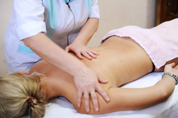 The massage back and shoulders close-up. Masseur in medical gown