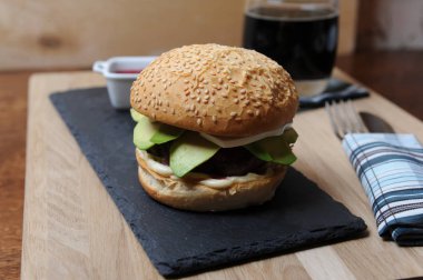 Burger, bira ve berry mazisi temel beyaz sos teknede, cam ve çatal bıçak takımı ahşap bir tahta üzerine sos,