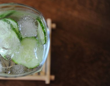 Ahşap masa üzerinde buz ile bir bardak taze salatalık yaz içeceği. Metin için boş alan