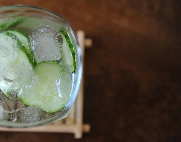 Fresh cucumber summer drink in a glass with ice on wooden table. Free space for text — Stock Photo, Image