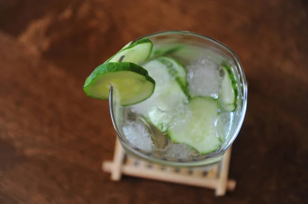 Fresh cucumber summer drink in a glass with ice on wooden table. Free space for text — Stock Photo, Image