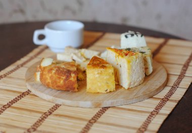 Peynir tabağı ve bir fincan kahve. Mindere yuvarlak ahşap tahta üzerinde çeşitli salamura peynir