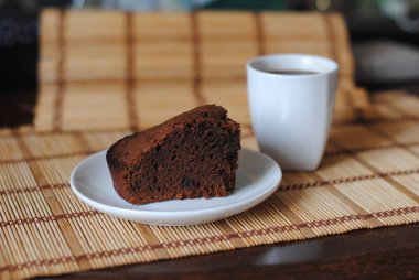 Bir mat üzerinde beyaz bir kase çikolata kek ve kahve bir parça. Close