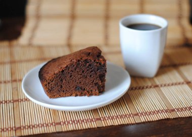 Bir mat üzerinde beyaz bir kase çikolata kek ve kahve bir parça. Close