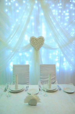 Beyaz masa dekorasyonu için restoranda yeni evliler. Arka ışık. Kalp perdelik