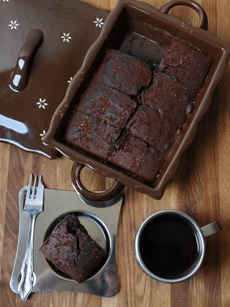 Bolinhos de chocolate em uma forma cerâmica. Pedaço de bolo e café em uma xícara de metal e pires — Fotografia de Stock