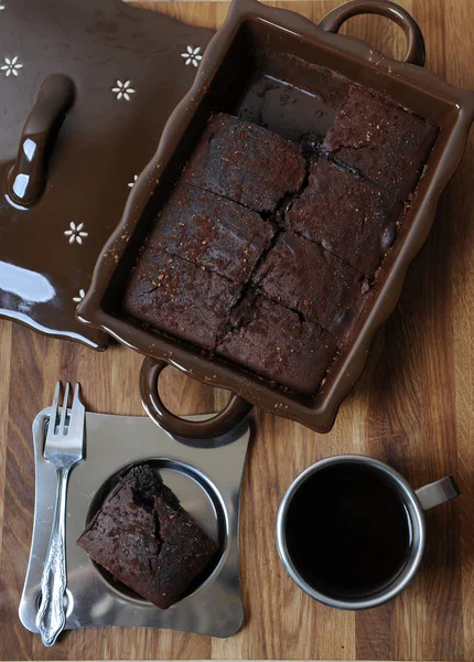 Bolinhos de chocolate em uma forma cerâmica. Pedaço de bolo e café em uma xícara de metal e pires — Fotografia de Stock