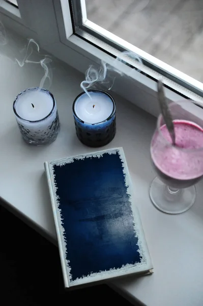 Pencere üzerinde blue tasarımı kapaklı defter. Duman, güler yüzlü içki uzun cam kadehi ile mumları — Stok fotoğraf