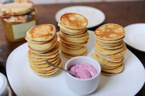 Panqueques con salsa de bayas en un plato blanco. Banco de mermelada en el fondo — Foto de Stock