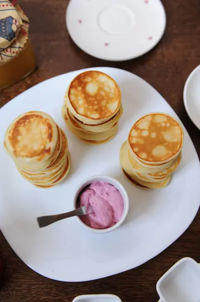 Panqueques con salsa de bayas en un plato blanco. Banco de mermelada en el fondo — Foto de Stock