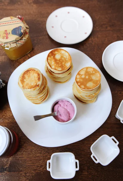 Panqueques con salsa de bayas en un plato blanco. Banco de mermelada en el fondo — Foto de Stock