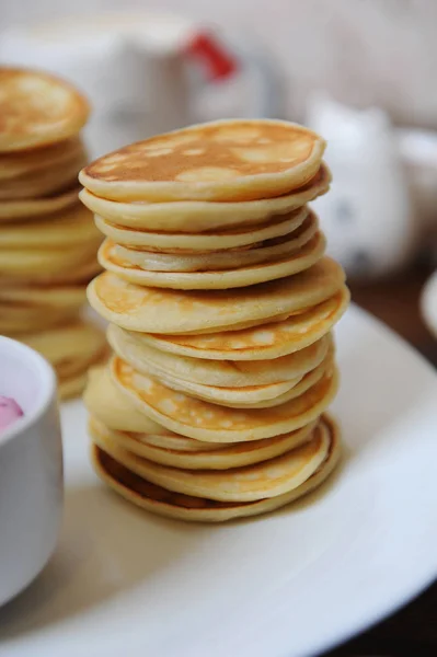 Pancakes with berry sauce on a white plate. On a wooden table closeup — Stock Photo, Image