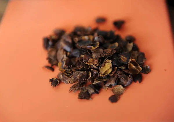 Het gedroogde vruchtvlees van de koffie bessen cascara is verspreid over het oranje oppervlak, close-up — Stockfoto