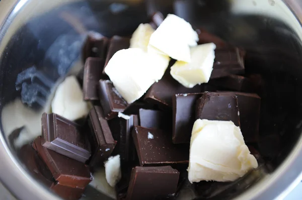 In einer Stahlschüssel schmelzen Schokoladen- und Butterstücke. der Prozess der Zubereitung von Süßigkeiten oder Dessert — Stockfoto