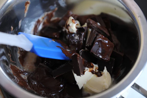 Schokolade und Butter schmelzen in einem Wasserbad. blauer Silikonspachtel. der Prozess der Zubereitung des Desserts oder der Süßigkeiten — Stockfoto