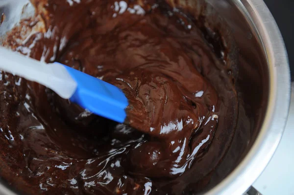Schokolade und Butter schmelzen in einem Wasserbad. blauer Silikonspachtel. der Prozess der Zubereitung des Desserts oder der Süßigkeiten — Stockfoto