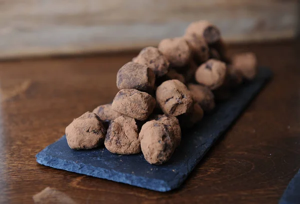 Trufas de chocolate en cacao espolvoreadas. En la pizarra sobre fondo de madera. Espacio libre para el diseño —  Fotos de Stock