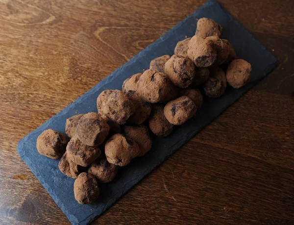 Chocolate truffles in cocoa sprinkled. On the slate board on wooden background. Free space for design — Stock Photo, Image