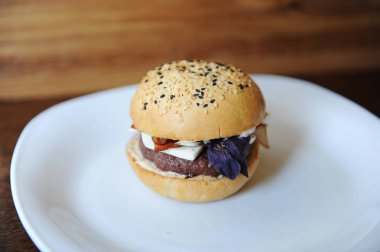 Burger beyaz tabakta. Ahşap arka plan