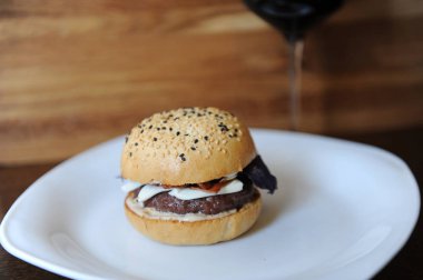 Burger ve ahşap arka plan üzerinde kırmızı şarap. Tasarım için boş alan