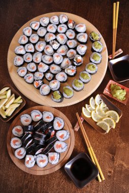 Ev yapımı suşi rulo. Sopa, limon, soya sosu, wasabi koyu kahverengi ahşap bir masa üzerinde servis edilir