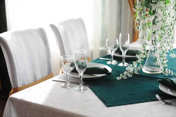 Mesa servida con luz solar en el restaurante. Arreglo floral, platos vacíos, vasos — Foto de Stock