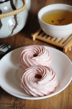 Beyaz daire, tatlı çatalı, su ısıtıcısı ve yeşil çay ile kase doğal çilek hatmi