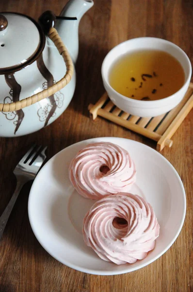 Земляничный зефир на белой тарелке, вилка для десерта, чайник и миска с зеленым чаем — стоковое фото