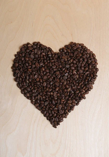 Grande coração feito de grãos de café em um fundo de madeira leve — Fotografia de Stock