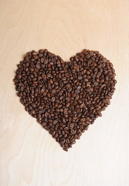 Grande coração feito de grãos de café em um fundo de madeira leve — Fotografia de Stock