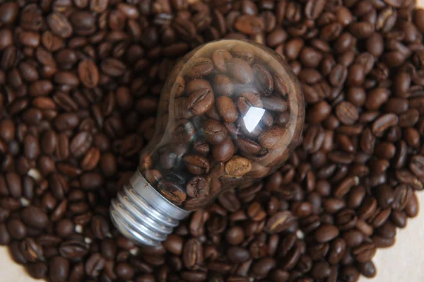 Bulb with coffee beans inside on a scattering of coffee