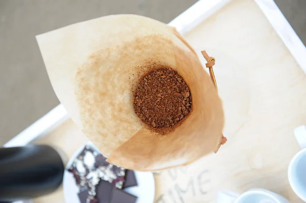 Café molido en un filtro de papel. Playa de arena en el fondo — Foto de Stock