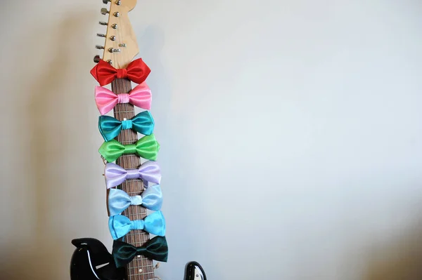 ギターのフレット ボード首に色とりどりの蝶ネクタイ。白い背景に、本文に空き — ストック写真