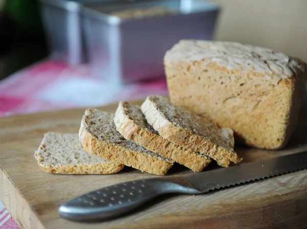 Świeże pieczywo na żyto ferment bez drożdży, cięte na pokładzie cięcia drewnianych na obrus w kratę — Zdjęcie stockowe