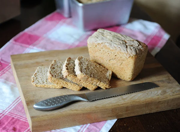 Pane fresco su un fermento di segale senza lievito tagliato su un tagliere di legno su una tovaglia a quadretti — Foto Stock