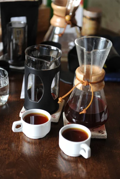 Two white cups and pitchers with coffee. Tasting and comparison