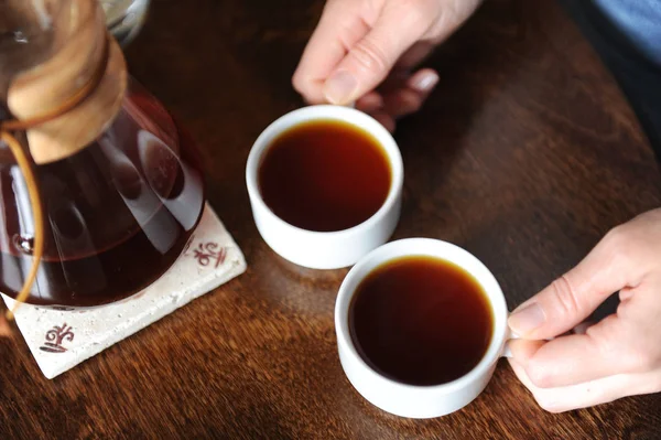 Две белые чашки с кофе в руках на столе — стоковое фото