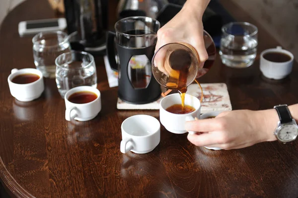 Pour freshly brewed coffee from a glass jug on white cups
