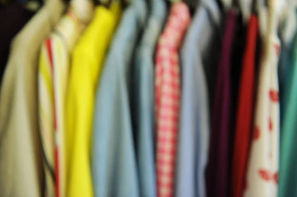 Textura borrosa de fondo de una fila de camisas y blusas de colores en una percha — Foto de Stock