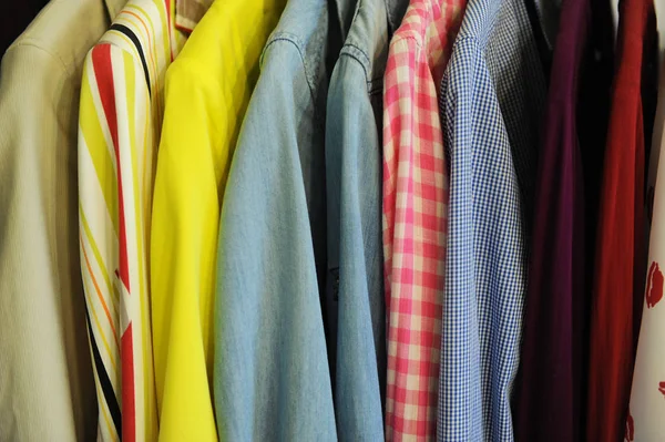 Textura de fondo de una fila de camisas y blusas de colores en una percha — Foto de Stock