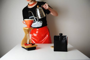 Moda barista kızı filtre kahve yapıyor. Odun damlatma istasyonu. Kırmızı deri etek, siyah tişört. Kazayağı su ısıtıcısı