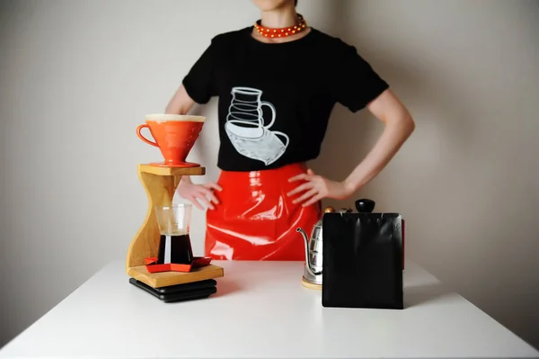 Trendy barista meisje brouwt filterkoffie. Houtdruppelstation. Rood lakleer rok, zwart t-shirt. — Stockfoto