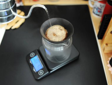 Black porous ceramic paperless coffee filter on glass jug. Gooseneck kettle. Electronic scale. Manual brewing still life