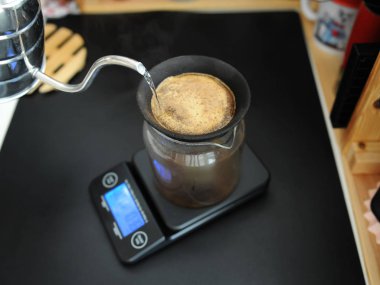Black porous ceramic paperless coffee filter on glass jug. Gooseneck kettle. Electronic scale. Manual brewing still life