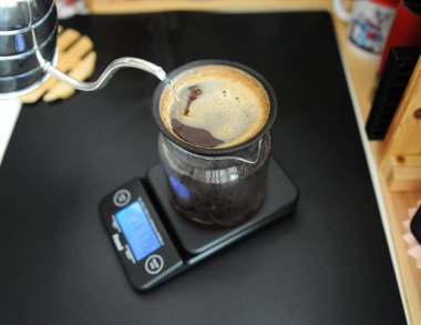 Black porous ceramic paperless coffee filter on glass jug. Gooseneck kettle. Electronic scale. Manual brewing still life