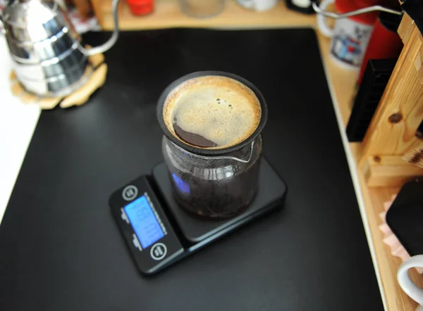 Zwarte poreuze keramische papierloze koffiefilter op glazen kan. Een ketel met zwanenhals. Elektronische weegschaal. Handmatig brouwen stilleven — Stockfoto