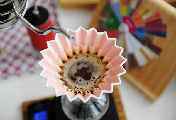 Альтернативное ручное пивоварение. Наливание воды в кофе в розовом оригами капельница с фильтром волны бумаги. Вид сверху, крупным планом — стоковое фото