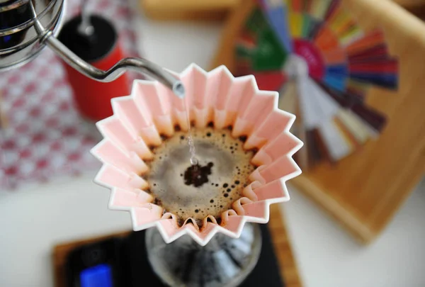 Alternative manual brewing. Pouring water in coffee in pink origami dripper with paper wave filter. Top view, close up — 图库照片