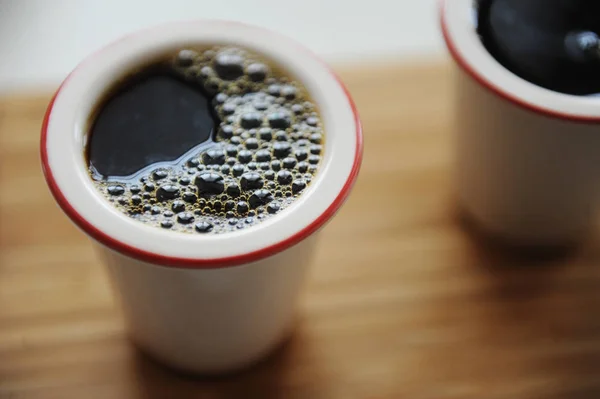 Φρέσκος μαύρος καφές φίλτρου σε δύο κεραμικά φλιτζάνια χωρίς λαβή σε δίσκο μπαμπού. Λευκό φόντο. Πάνω όψη, κλείστε. — Φωτογραφία Αρχείου
